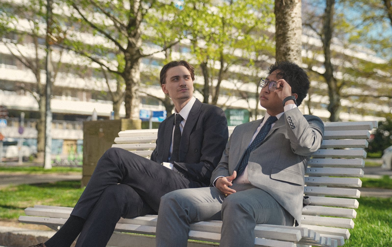 Two men in tailored suits on a bench in Vaasa