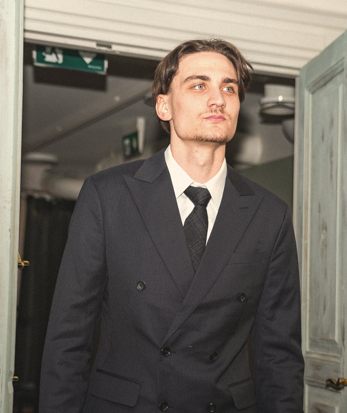 A man in a tailored dark suit standing in a doorway in Vaasa